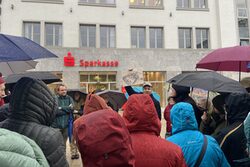 Florian Schrader, Leiter des Denkmalschutzes, steht in der Mitte der Teilnehmenden und hält ein historisches Bild von Elberfeld hoch.